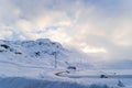 Winter snow covers mountains and road in Switzerland with background of  beautiful evening sun light and clouds Royalty Free Stock Photo