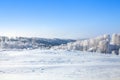 Winter snow forest and field landscape, white trees covered with hoar frost, hills, snow drifts on bright blue sky background Royalty Free Stock Photo