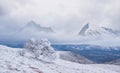 Winter snowbound mountain slope with alone tree under a dense cloudy sky Royalty Free Stock Photo