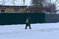 A man with a backpack on his shoulders is walking along a snow-covered road. Royalty Free Stock Photo