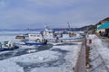 Winter snowy port with white ships on the icy shore of baikal, blue mountains in background