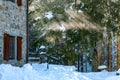 Winter and snowy rural scene with stone house and sun rays breaking through the trees Royalty Free Stock Photo