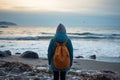 Winter solitude Girl in down jacket stands on seashore contemplating