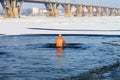 Winter sport. An elderly man swims in a winter river covered with ice during the Orthodox holiday Epiphany. Hardening