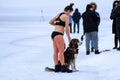 Winter sport, hardening in winter. A girl in a bathing suit with a dog stands near a river covered with ice and snow. Orthodox