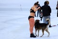 Winter sport, hardening in winter. A girl in a bathing suit with a dog stands near a river covered with ice and snow.