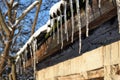 Winter spring. Icicles hang from the wooden roof, sparkling in the sunlight. The snow melts. Royalty Free Stock Photo