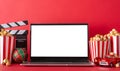 Winter staycation: side view of laptop, popcorn, baubles, movie clapper red wall backdrop for advertising