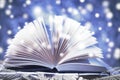 Winter story. Open book on wooden snowy blue background