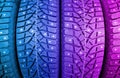 Winter studded tire in blue and pink tones. Winter car tires background. Tire stack background. Tyre protector close up. Square