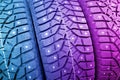 Winter studded tire. Winter car tires background. Tire stack background. Tyre protector close up in pink and blue tones. Black