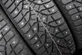 Winter studded tire. Winter car tires background. Tire stack background. Tyre protector close up. Square powerful spikes. Black