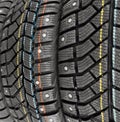 Winter studded tire. Winter car tires background. Tire stack background. Tyre protector close up. Square powerful spikes. Black
