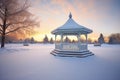 winter sunrise casting glow on snow-wrapped gazebo