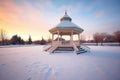 winter sunrise casting glow on snow-wrapped gazebo