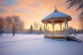 winter sunrise casting glow on snow-wrapped gazebo