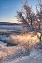 Winter sunrise landscape with trees in snow, Faxi waterfall and steam over water Royalty Free Stock Photo
