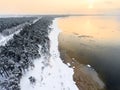 Winter sunset on the Baltic sea, snow covered sandy beach line, evergreen trees and open water, the Gulf of Finland, St. Royalty Free Stock Photo