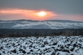 Winter sunset over arable land and snowy hills Royalty Free Stock Photo