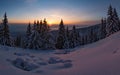 Winter sunset snow field on top of mountain with frosty pine trees on the background of taiga forest and hills under colorful sky.