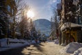 A winter tale - a sunny day for Christmas. Snow-covered streets, houses, sun rays, people walking along the pedestrian zone. ski