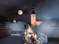  Tallinn old town blue sky and full moon snow on medieval tower roof night street blurred light panorama travel to Estonia