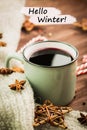 Winter theme. Hot steaming cup of glint wine with spices, cinnamon, anise, red candies, pepper and gray scarf on wooden background