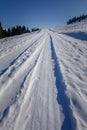 Winter, thick ice and snow cover the road, the road stretches to the distance under the blue sky