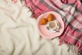 Winter time. A cozy warm pink blanket and a cup of coffee and croissants on the bed