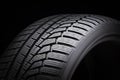 Winter tire, driving safety on snowy and icy roads. asymmetric tread pattern. close-up on a black background Royalty Free Stock Photo