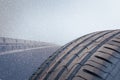 Winter tire in the foreground is on a road that is snowing Royalty Free Stock Photo