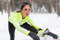 Winter training Fitness model athlete girl warm up stretching her hamstrings, leg and back.