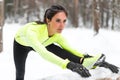 Winter training Fitness model athlete girl warm up stretching her hamstrings, leg and back.