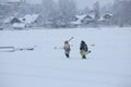 Two fishermen are coming back at their village after fishing on ice of lake Royalty Free Stock Photo