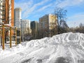 Winter urban landscape, houses, large snowdrift on sports ground, clear day