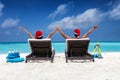 Happy couple wearing santa hats in sun chairs on a tropical beach during Christmas time Royalty Free Stock Photo