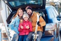 Winter vacation. Family time together outdoors standing sitting at car trunk with skis smiling excited girl showing Royalty Free Stock Photo