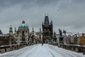 Winter view of Charles bridge, Old Town bridge tower covered with snow, Prague, Czech Republic. People walking through the city in