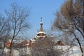Winter. View of the Christian wooden church through trees. Temple of the Holy Martyr John the Warrior in Novokuznetsk, Russia