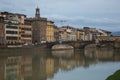 Winter view of the famous Ponte Vecchio old bridge, a medieval stone closed-spandrel segmental arch bridge over the Arno River in Royalty Free Stock Photo