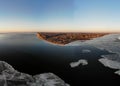 Winter view of little city on clay hills near the Dnieper estuary. The water is partially covered with ice.