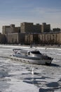 Winter view of the Moscow river embankment and cruise yacht sailing on iced water