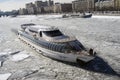 Winter view of the Moscow river embankment and cruise yacht sailing on iced water