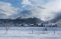 Winter village landscape, wooden houses and church in the countryside in fog at sunset in mountains Royalty Free Stock Photo