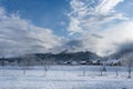 Winter village landscape, wooden houses and church in the countryside in fog at sunset in mountains Royalty Free Stock Photo