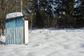 Winter in the village. Small house in a snowy field. Sheds in the snow