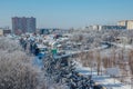 Winter Voronezh cityscape. Frozen trees in a forest covered by snow and hoarfrost near modern houses in the city of Voronezh Royalty Free Stock Photo