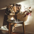 Winter warm blanket on a chair with a basket of Christmas decorations, books and led string lights. HOME. Winter reading. House Royalty Free Stock Photo