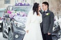 Winter wedding, the happy couple before the decorated car on a snowy street. Bride and groom look at each other.