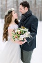 Winter wedding, stylish young couple, bride and groom, in the forest, tender hugs. Bride with long hair in cotton wreath Royalty Free Stock Photo